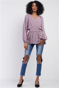 Image of a lilac v-neck blouse with button-down detailing, a self-tie waist, and peasant long sleeves. 